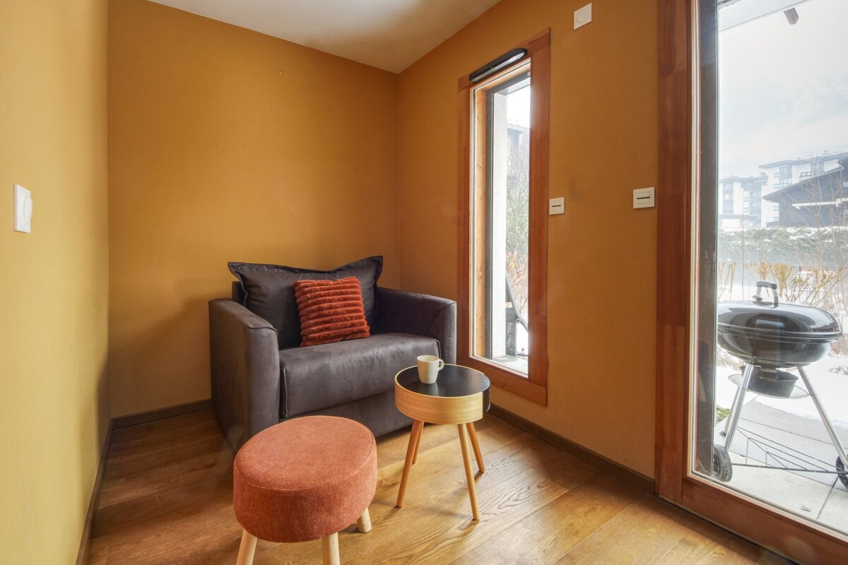 A chair with an orange pillow sits next to a small table