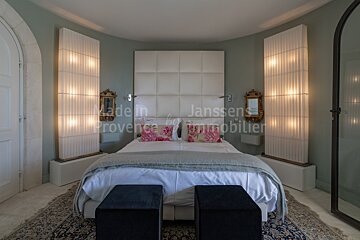 A bedroom with a bed and two ottomans and the word janssens on the wall