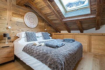 A bedroom with a large bed and a skylight