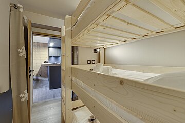 A wooden bunk bed in a room with a door