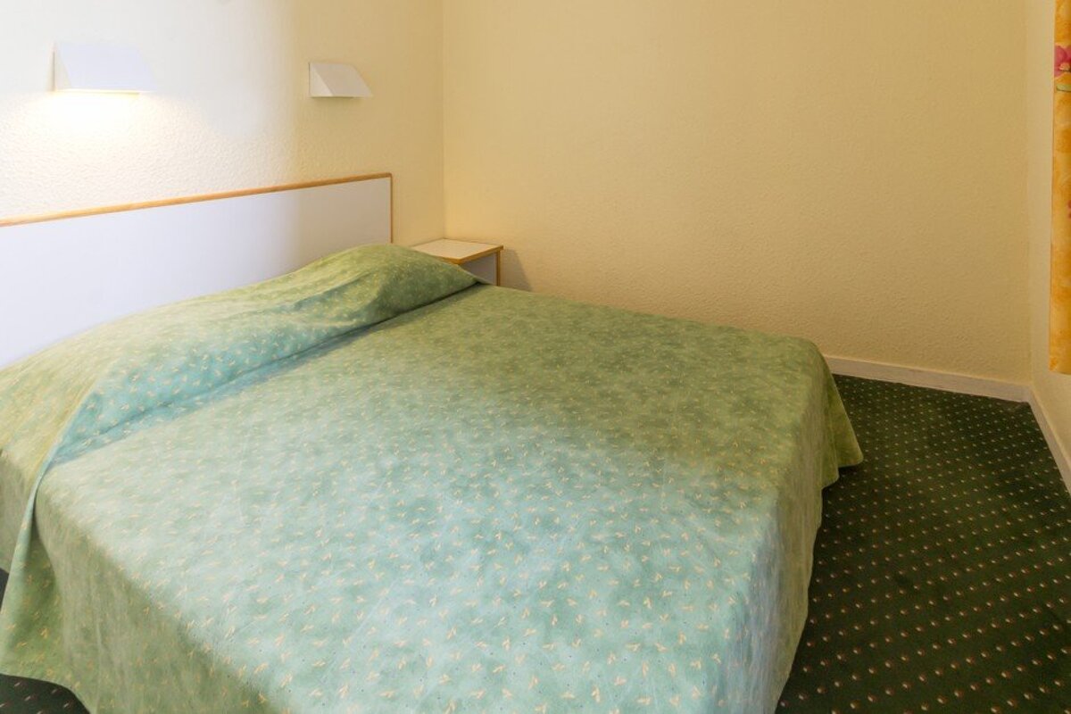 A hotel room with a green bed and green carpet