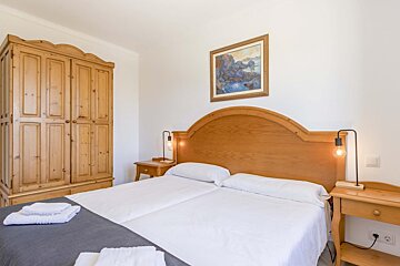 A bedroom with a painting on the wall above the bed