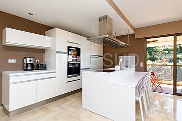 A kitchen with white cabinets and stainless steel appliances has a sliding glass door that leads to a balcony
