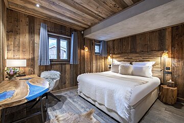 A bedroom with a large bed and a wooden desk