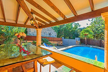 A table with a vase of flowers sits in front of a swimming pool