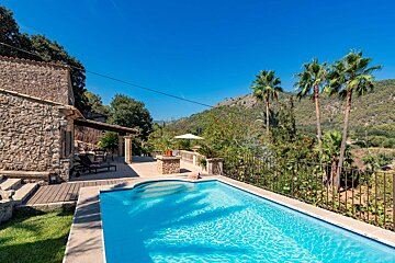 A large swimming pool in front of a stone house
