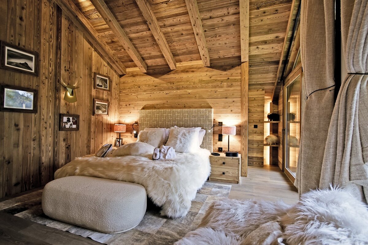 A bedroom with wooden walls and a bed with fur on it