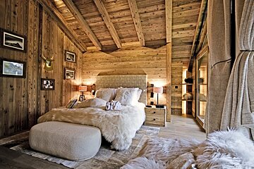 A bedroom with wooden walls and a bed with fur on it