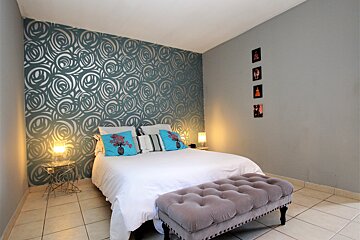 A bedroom with a bed and a gray ottoman