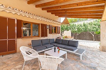 A patio with a couch and a table with a bottle of wine on it