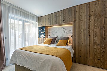 A bed with a yellow blanket and pillows in a bedroom