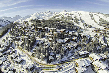 An aerial view of a snow covered village with mountains in the background