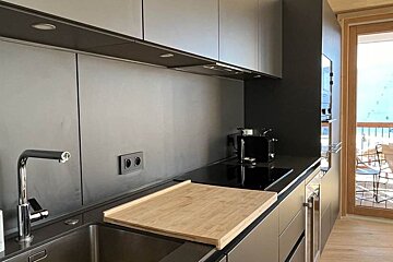 A kitchen with a stainless steel sink and a wooden cutting board