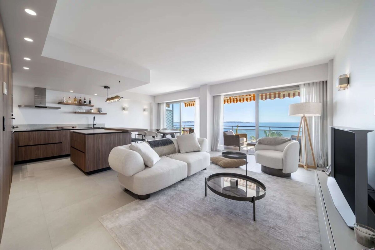 Bright, open-plan living space with a modern kitchen, comfortable seating, and a large balcony offering panoramic sea views.