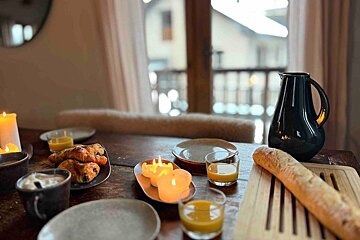 A table with plates candles and glasses of orange juice