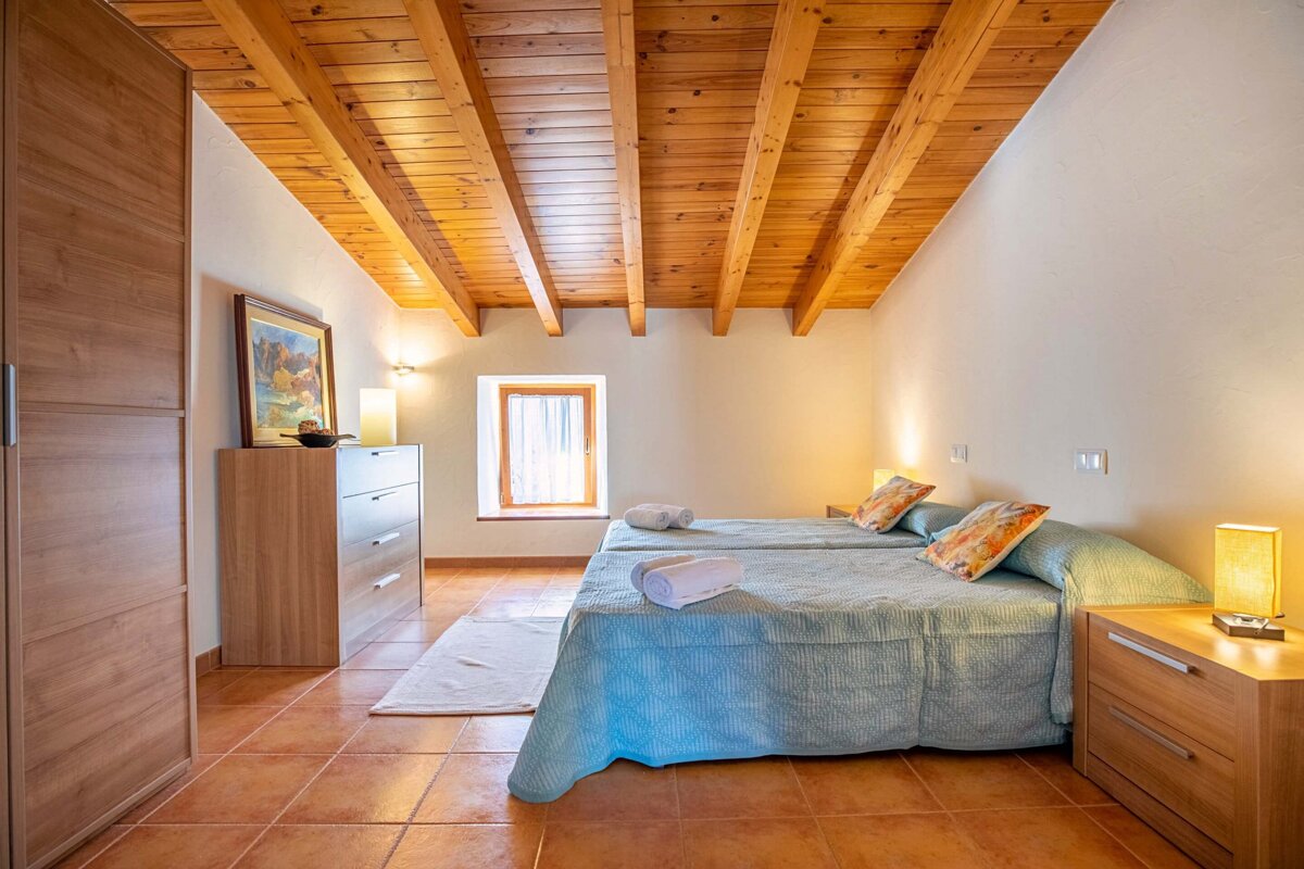 A bedroom with two beds and a wooden ceiling