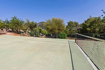 A tennis court with trees and a mountain in the background