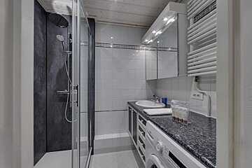 A bathroom with a washing machine a sink and a shower