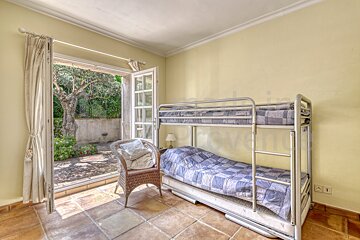 A bedroom with a bunk bed and a wicker chair