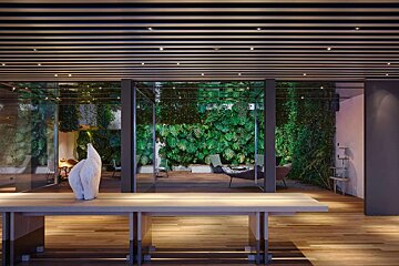 A room with a table and a wall of plants