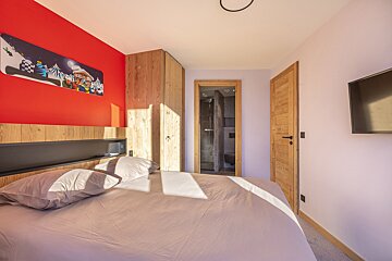 A bedroom with a red wall and a bed