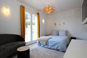 A bedroom with a bed a couch and a television