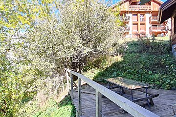 A wooden deck with a picnic table in front of a house