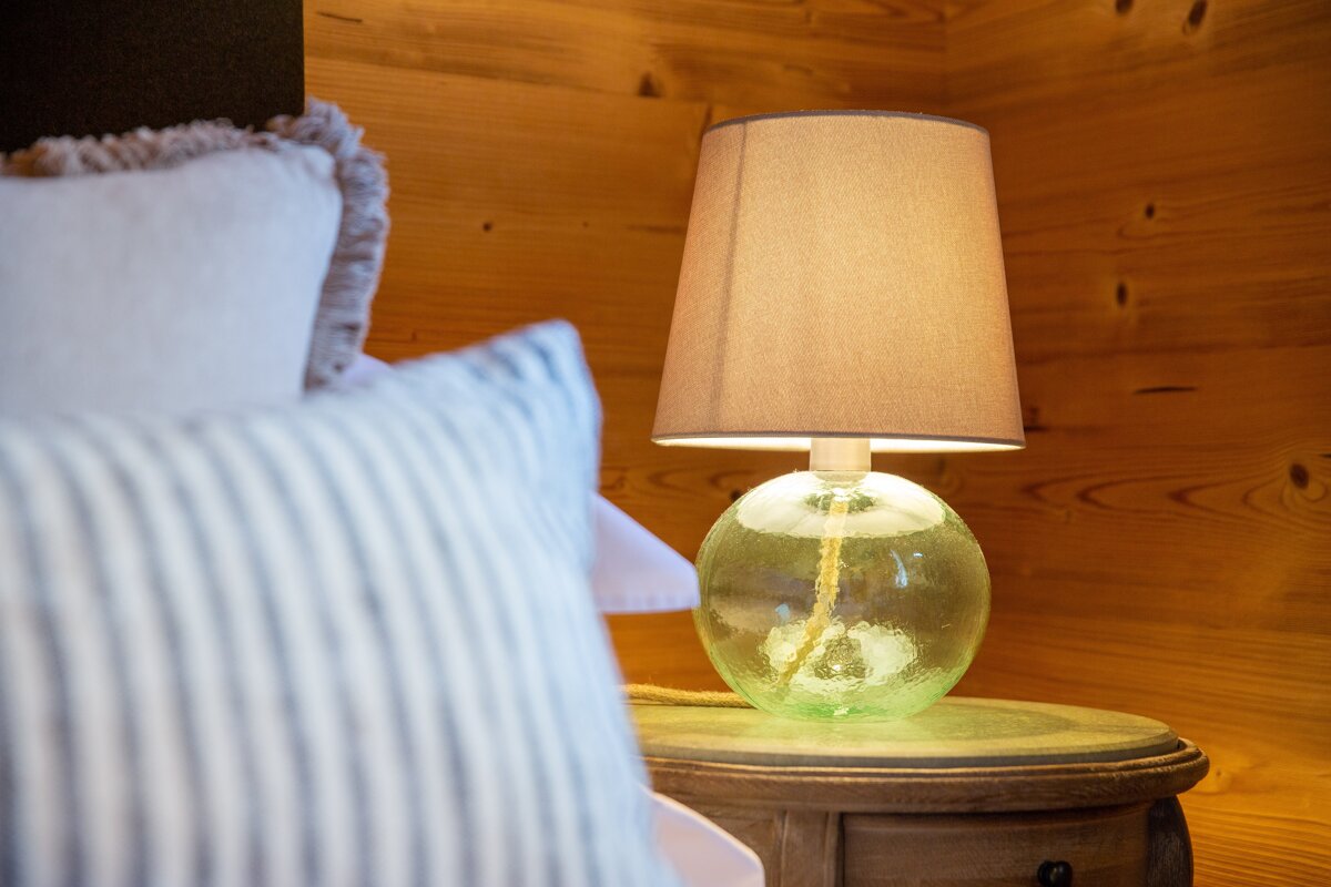 A lamp sits on a nightstand next to a bed