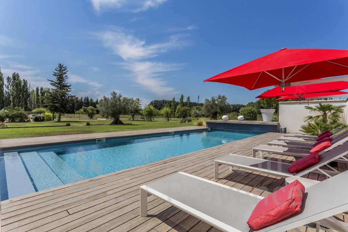 A swimming pool surrounded by lounge chairs and red umbrellas