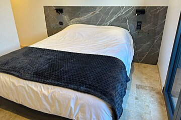 A bed with white sheets and a black blanket