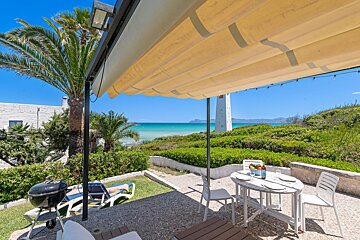 A patio with a table and chairs overlooking the ocean