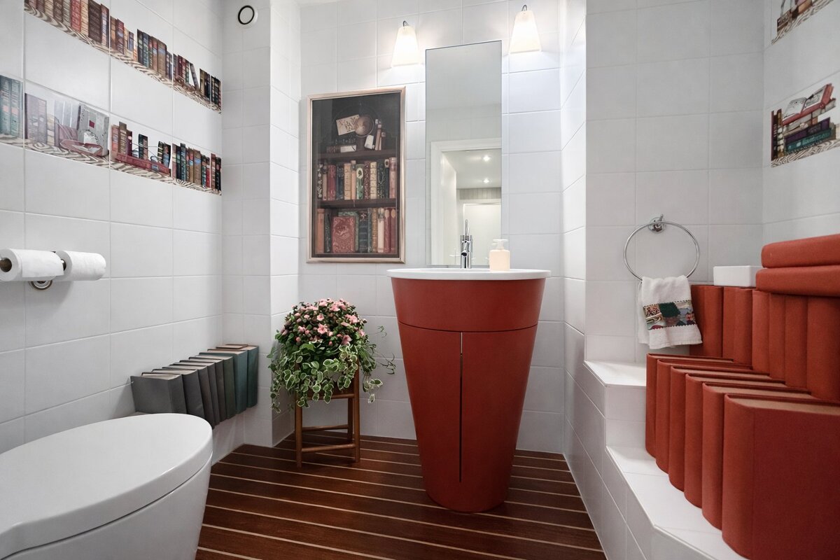 A bathroom with a book theme, featuring a terracotta sink, matching faux book decorations, and white tile walls.