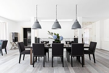 A dining room with a table and chairs and a vase of flowers