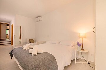 A bedroom with a large bed and a lamp