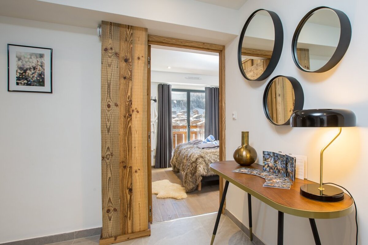 A hallway with a wooden door leading to a bedroom