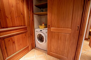 A washer and dryer in a closet with wooden doors