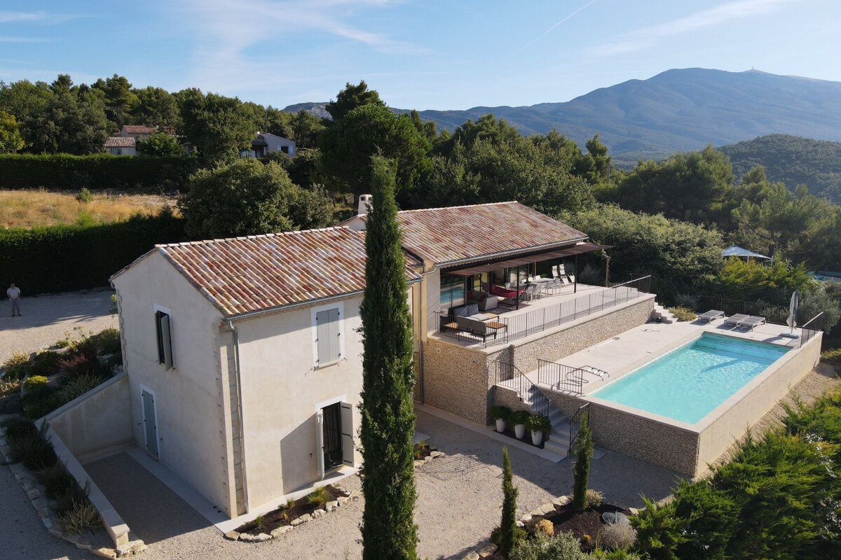 An aerial view of a house with a pool and mountains in the background