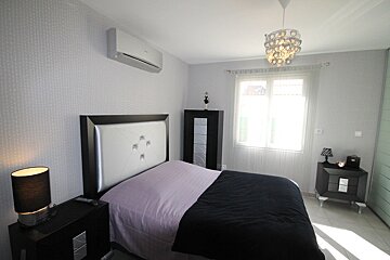 A bedroom with a bed a nightstand and a lamp