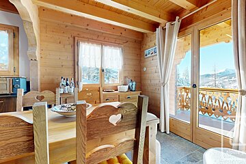 A wooden house with a dining table and chairs