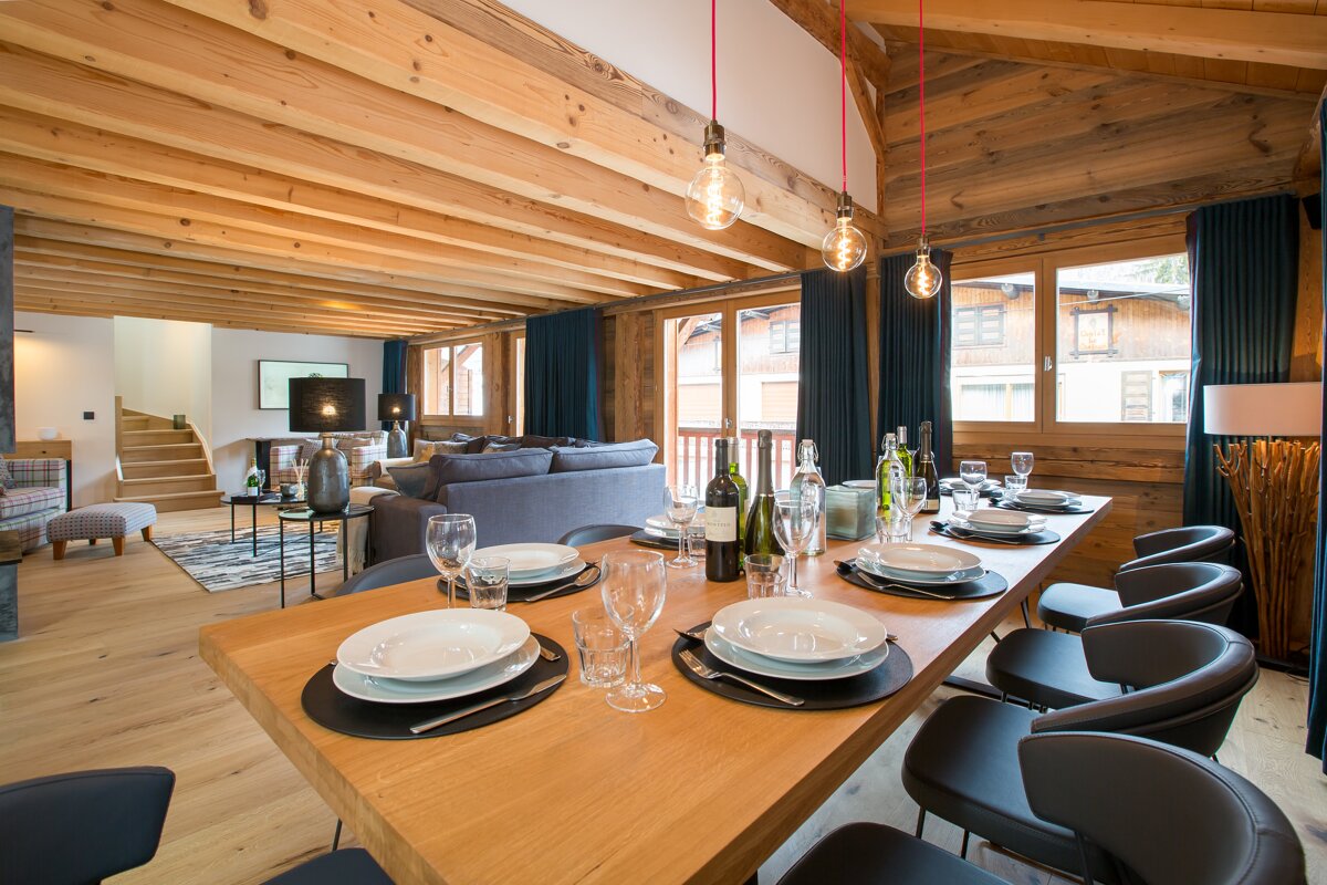 A dining room table with plates and glasses and a bottle of wine on it
