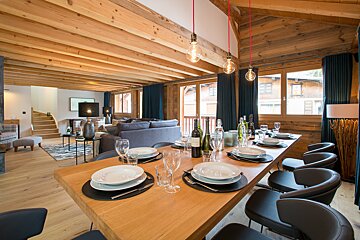 A dining room table with plates and glasses and a bottle of wine on it