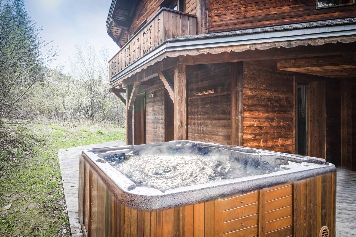 A hot tub sits outside of a wooden house