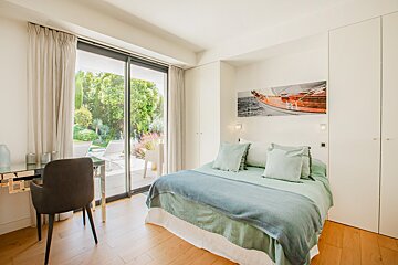 A bedroom with a painting of a boat on the wall above the bed