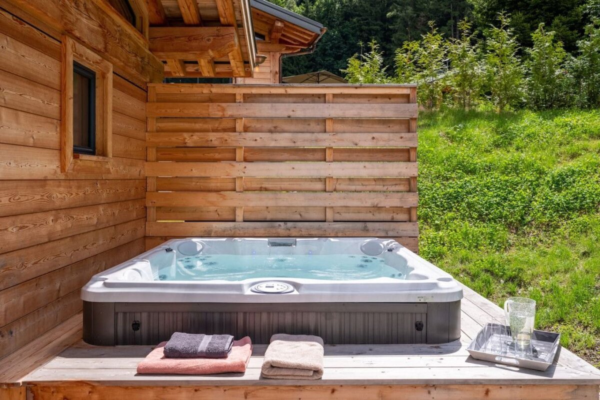 A hot tub sits outside of a wooden house