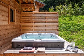 A hot tub sits outside of a wooden house