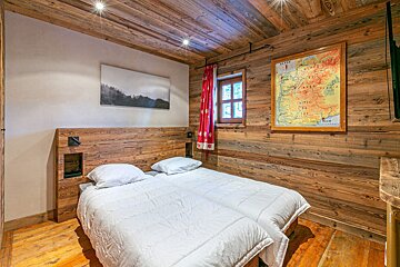 A wooden room with a bed and a chair