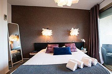A bedroom with a bed a mirror and a clock on the wall