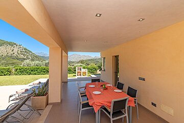 A table and chairs on a patio with mountains in the background