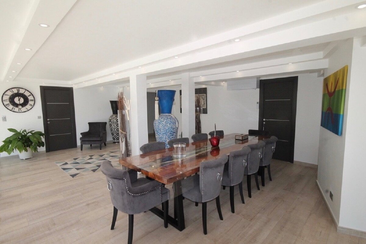 A dining room with a table and chairs and a clock on the wall