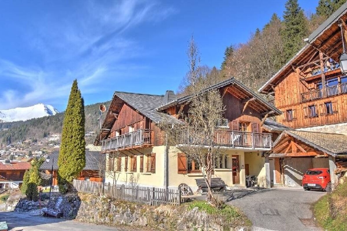 Traditional wooden chalets nestled in a mountainous landscape under a bright blue sky.